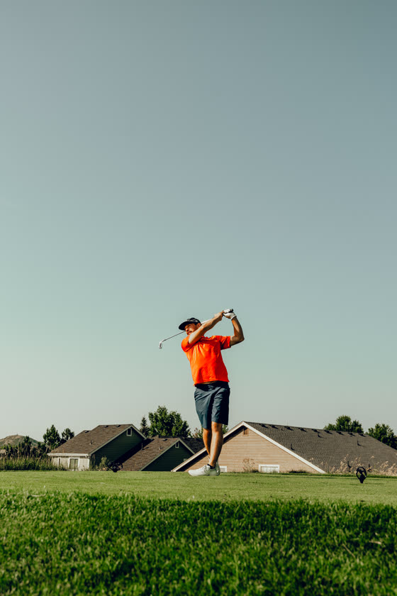 Golfer at the top of a swing on a course at sunset