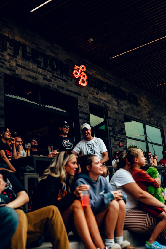 Guests filling a Colorado taproom under a neon sign