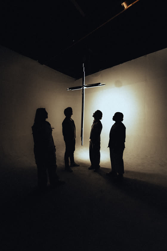 Silhouettes gathered in front of an illuminated cross