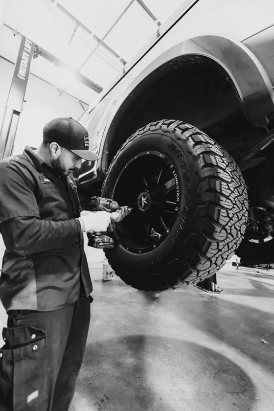 Technician mounting an off-road tire in a truck shop