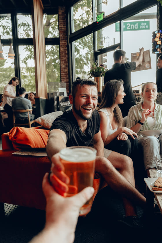Toasting a beer with friends in a sunlit Colorado taproom