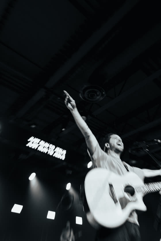 Worship leader with an acoustic guitar under stage lights
